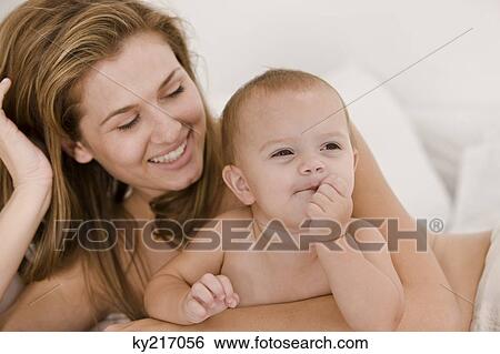 Close-up of a woman carrying her daughter View Large Photo Image Stock Photograph - Close-up of a woman carrying her daughter. Fotosearch