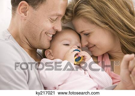 Stock Image - Parents pampering their daughter. Fotosearch