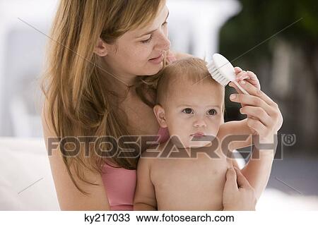 Stock Image - Woman brushing her daughter's hair. Fotosearch