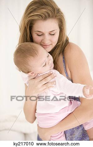 Stock Image - Woman carrying her daughter. Fotosearch