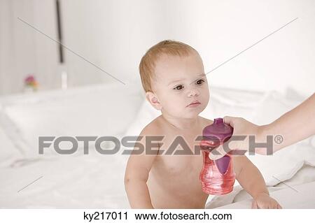 Stock Image - Woman giving a baby bottle to her daughter. Fotosearch