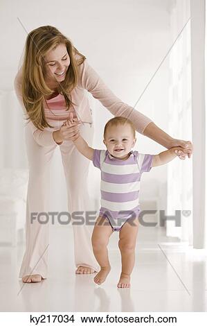 Woman helping her daughter to walk View Large Photo Image Picture - Woman helping her daughter to walk. Fotosearch