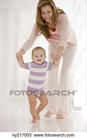Woman helping her daughter to walk View Large Photo Image Stock Image - Woman helping her daughter to walk. Fotosearch