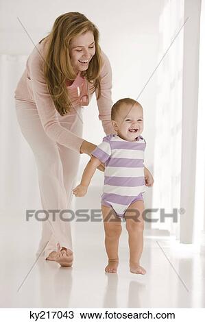 Woman helping her daughter to walk View Large Photo Image Stock Image - Woman helping her daughter to walk. Fotosearch
