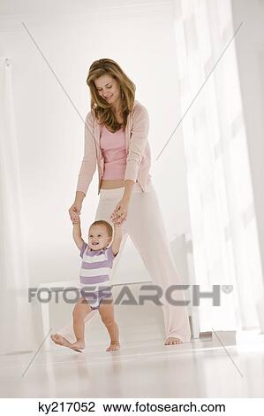 Stock Image - Woman helping her daughter to walk. Fotosearch