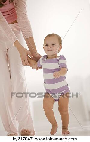 Stock Photo - Woman helping her daughter to walk. Fotosearch