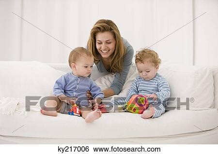 Woman playing with her son and daughter on a couch View Large Photo Image Stock Photograph - Woman playing with her son and daughter on a couch. Fotosearch
