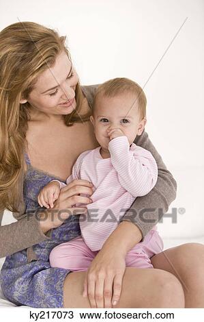 Stock Image - Woman with her daughter sitting on her lap. Fotosearch