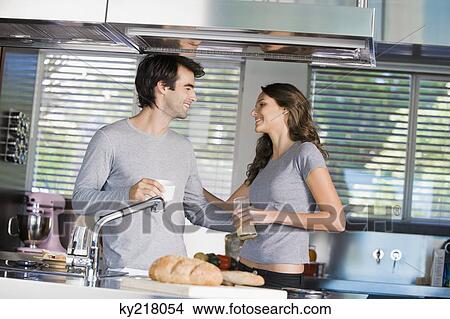 Couple having breakfast and smiling at each other in the kitchen View Large Photo Image Picture - Couple having breakfast and smiling at each other in the kitchen. Fotosearch