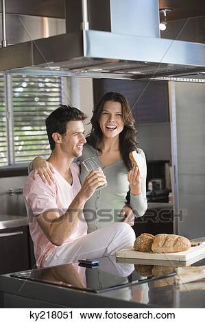 Stock Image - Couple having breakfast in the kitchen. Fotosearch