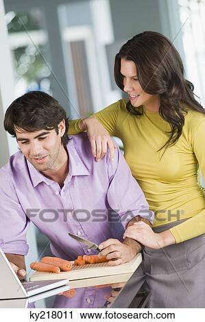 Man cooking with the recipe on a laptop and a woman standing beside him View Large Photo Image Stock Image - Man cooking with the recipe on a laptop and a woman standing beside him. Fotosearch