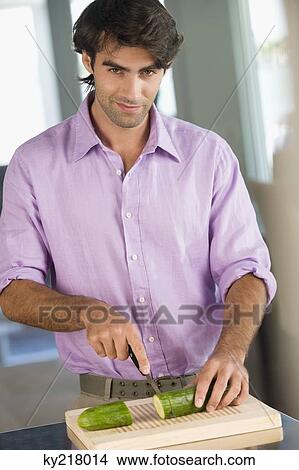 Picture - Man cutting a cucumber. Fotosearch