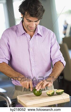 Stock Image - Man cutting avocado and smiling. Fotosearch