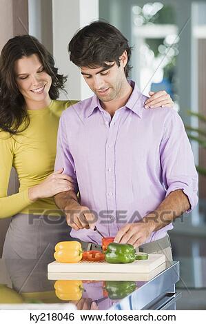 Stock Photograph - Man cutting bell peppers with a woman standing beside him. Fotosearch