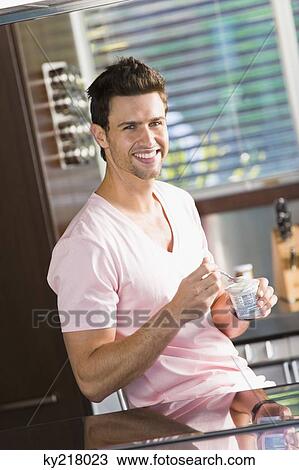 Man eating yogurt in the kitchen View Large Photo Image Stock Image - Man eating yogurt in the kitchen. Fotosearch