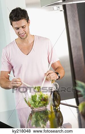 Man mixing vegetable salad in the kitchen View Large Photo Image Stock Photo - Man mixing vegetable salad in the kitchen. Fotosearch
