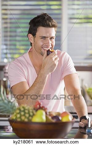 Stock Image - Portrait of a man eating a nectarine. Fotosearch