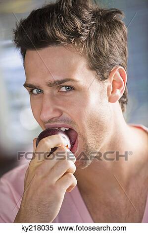 Stock Photography - Portrait of a man eating a nectarine. Fotosearch