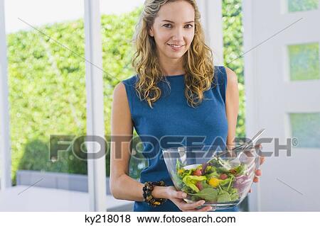 Portrait of a woman holding salad in a mixing bowl and smiling View Large Photo Image Stock Photo - Portrait of a woman holding salad in a mixing bowl and smiling. Fotosearch