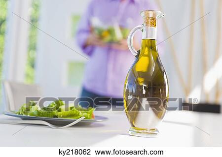 Stock Image - Salad oil with a plate of salad on a dining table. Fotosearch