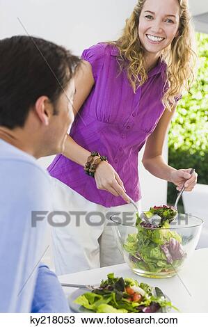 Woman serving salad to her husband and smiling View Large Photo Image Stock Image - Woman serving salad to her husband and smiling. Fotosearch