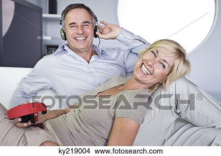 Picture - Couple listening to music with headphones and smiling. Fotosearch