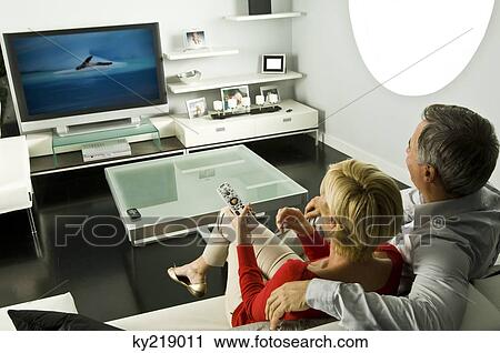 Stock Image - Couple watching television on a couch. Fotosearch