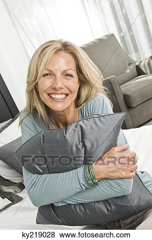 Woman hugging a pillow and smiling View Large Photo Image Stock Photo - Woman hugging a pillow and smiling. Fotosearch