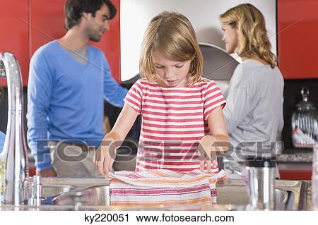 Girl holding dish cloth with her parents standing in the background View Large Photo Image Stock Image - Girl holding dish cloth with her parents standing in the background. Fotosearch