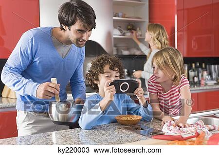 Stock Image - Man with his children in the kitchen. Fotosearch