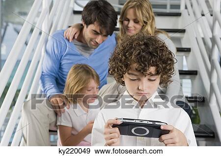 Parents sitting on steps with their children playing video games View Large Photo Image Stock Photo - Parents sitting on steps with their children playing video games. Fotosearch