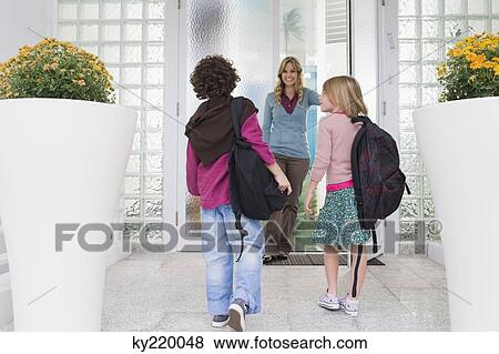 Stock Photo - Woman with her children at the entrance door of a house. Fotosearch