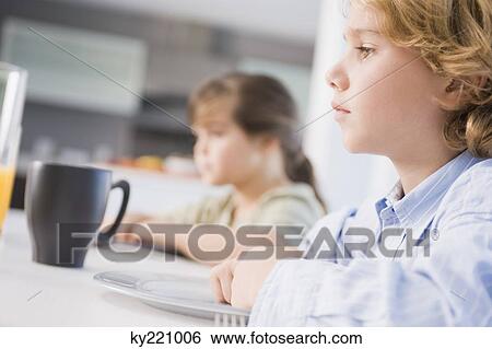 Boy and a girl at a dining table View Large Photo Image Stock Photograph - Boy and a girl at a dining table. Fotosearch