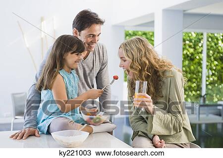Girl feeding fruit salad to her mother View Large Photo Image Stock Image - Girl feeding fruit salad to her mother. Fotosearch