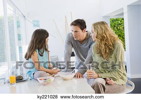 Stock Photo - Girl with her parents at the breakfast table. Fotosearch