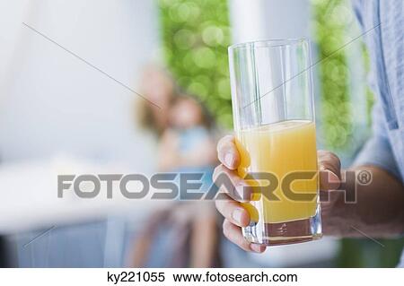 Man's hand holding a glass of juice View Large Photo Image Stock Photography - Man's hand holding a glass of juice. Fotosearch