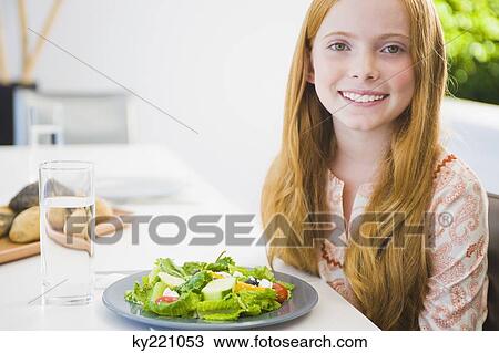Stock Image - Portrait of a girl eating salad and smiling. Fotosearch