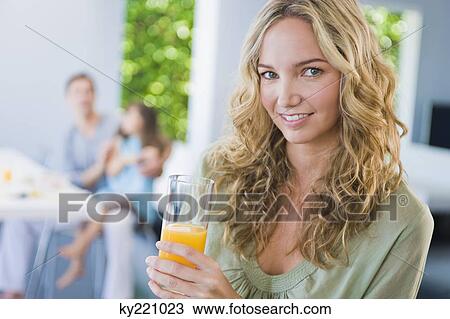 Portrait of a woman drinking a glass of juice and smiling View Large Photo Image Stock Image - Portrait of a woman drinking a glass of juice and smiling. Fotosearch