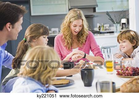 Woman checking the time and having breakfast with her family View Large Photo Image Stock Image - Woman checking the time and having breakfast with her family. Fotosearch