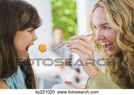 Woman feeding fruit salad to her daughter View Large Photo Image Stock Image - Woman feeding fruit salad to her daughter. Fotosearch