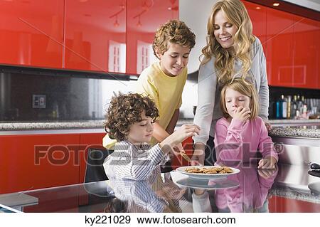 Woman with her children eating cookies in the kitchen View Large Photo Image Stock Photo - Woman with her children eating cookies in the kitchen. Fotosearch