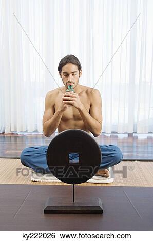 Stock Photograph - Man smelling aromatherapy oil from a bottle. Fotosearch