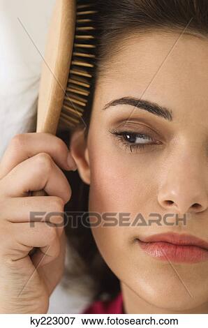 Close-up of a woman brushing her hair View Large Photo Image Stock Photo - Close-up of a woman brushing her hair. Fotosearch