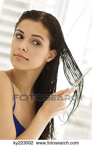 Stock Image - Close-up of a woman combing her hair. Fotosearch