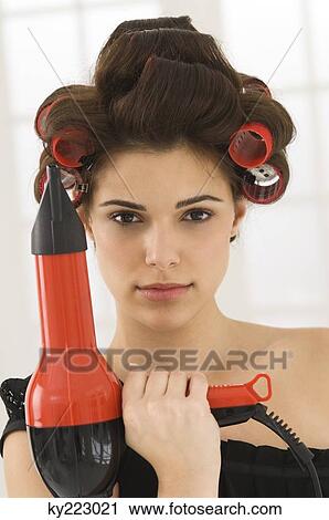 Stock Image - Portrait of a woman holding a hair dryer. Fotosearch