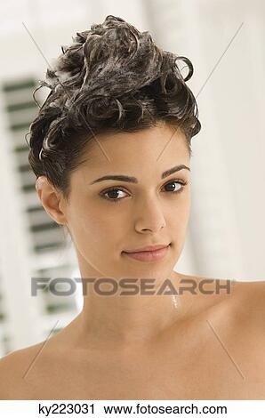 Stock Image - Portrait of a woman shampooing her hair. Fotosearch