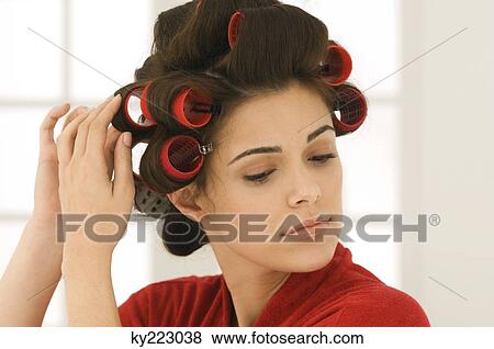 Stock Photo - Woman adjusting curlers in her hair. Fotosearch
