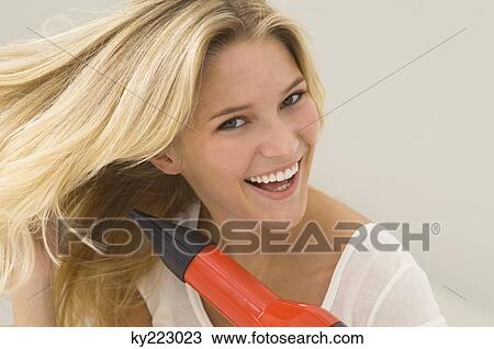 Woman drying her hair with a hair dryer View Large Photo Image Stock Image - Woman drying her hair with a hair dryer. Fotosearch