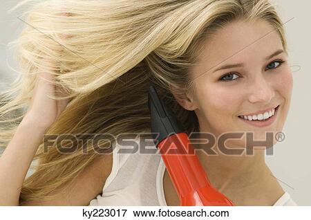 Woman drying her hair with a hair dryer View Large Photo Image Stock Photo - Woman drying her hair with a hair dryer. Fotosearch