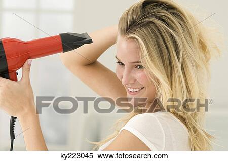 Woman drying her hair with a hair dryer View Large Photo Image Stock Photography - Woman drying her hair with a hair dryer. Fotosearch